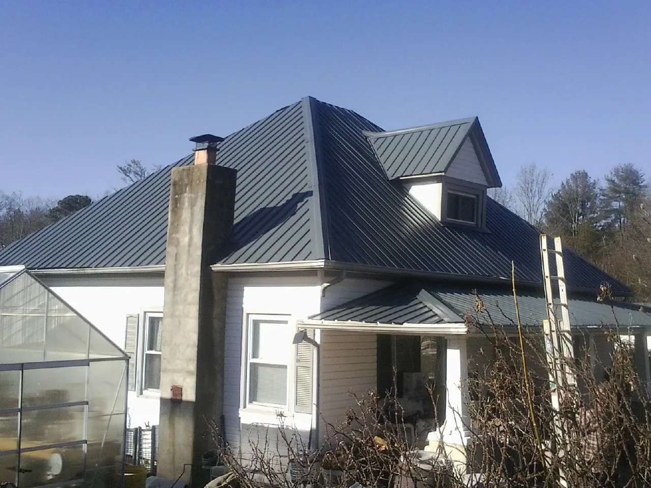 Dark blue standing seam metal roof on a white farmhouse with dormer — Slate & Tile Roof Repair by Roofing Brothers in Hillburn