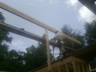Carpenter setting a ridge beam over a new addition frame — Ice Dam Removal by Roofing Brothers in Hillburn