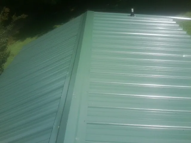 New green metal panels meeting at the ridge of a roof — Flat Roof Repair work by our crew in Hillburn