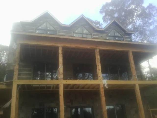 Dormers and porch framing on a large log home under construction — Roof Coating work by our crew in Hillburn