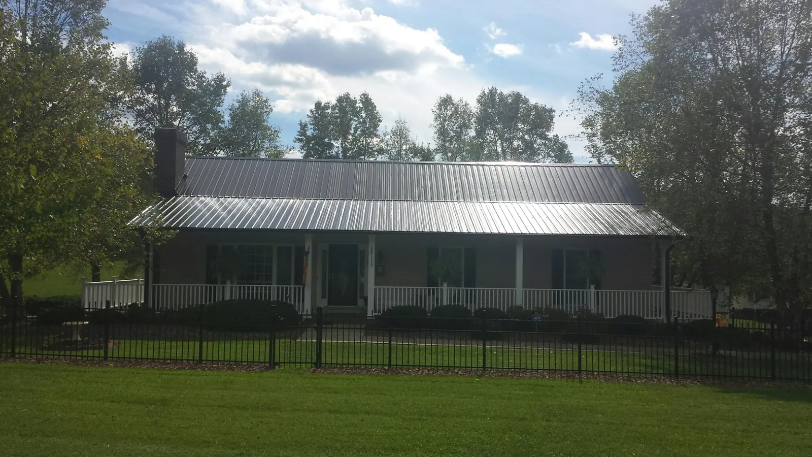 Gray metal roof on a brick ranch with a full width front porch — Gutter Guard Installation work by our crew in Hillburn