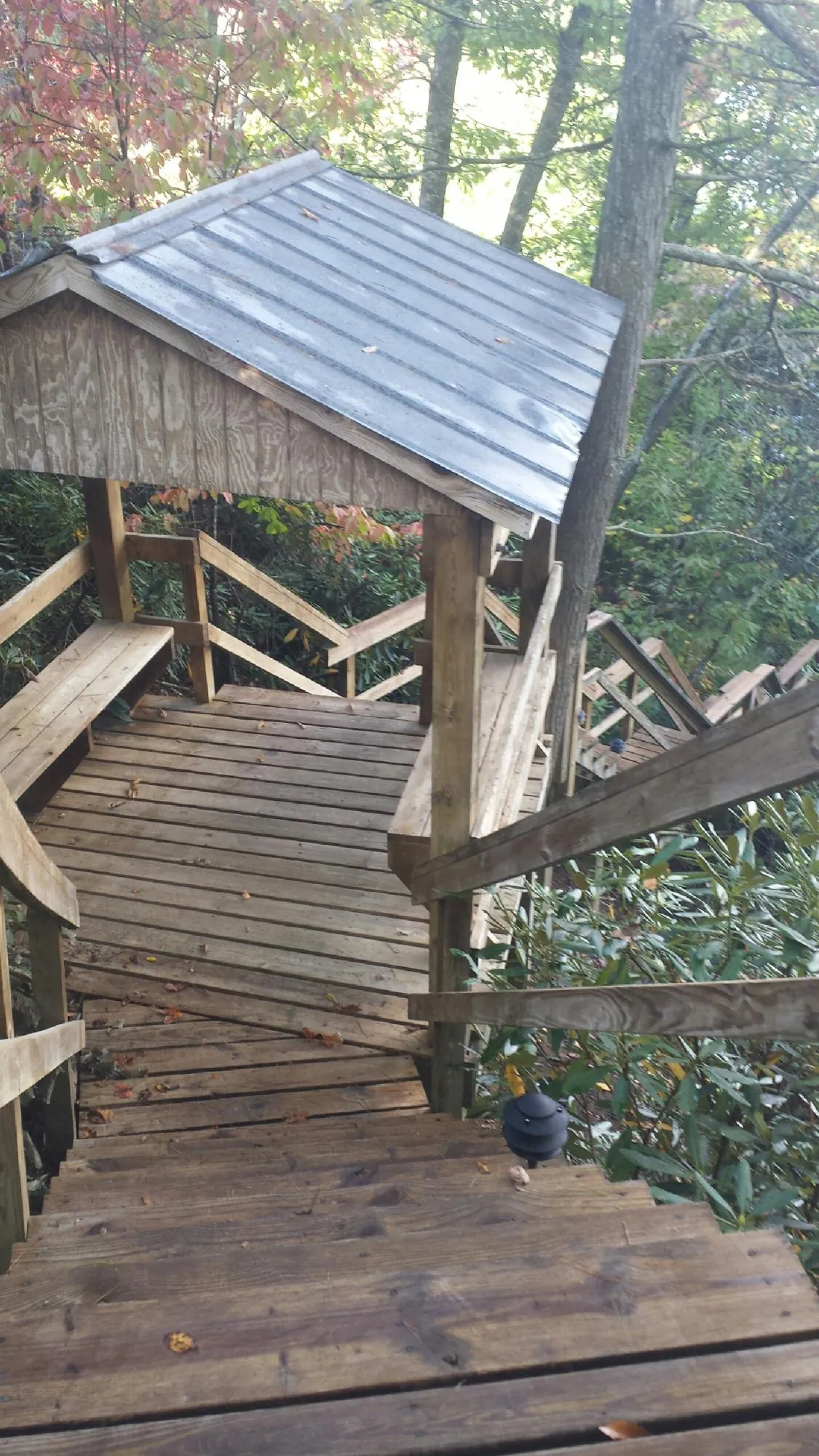 Metal roofed shelter over wooden steps on a wooded walkway — Skylight Repair & Installation work by our crew in Hillburn