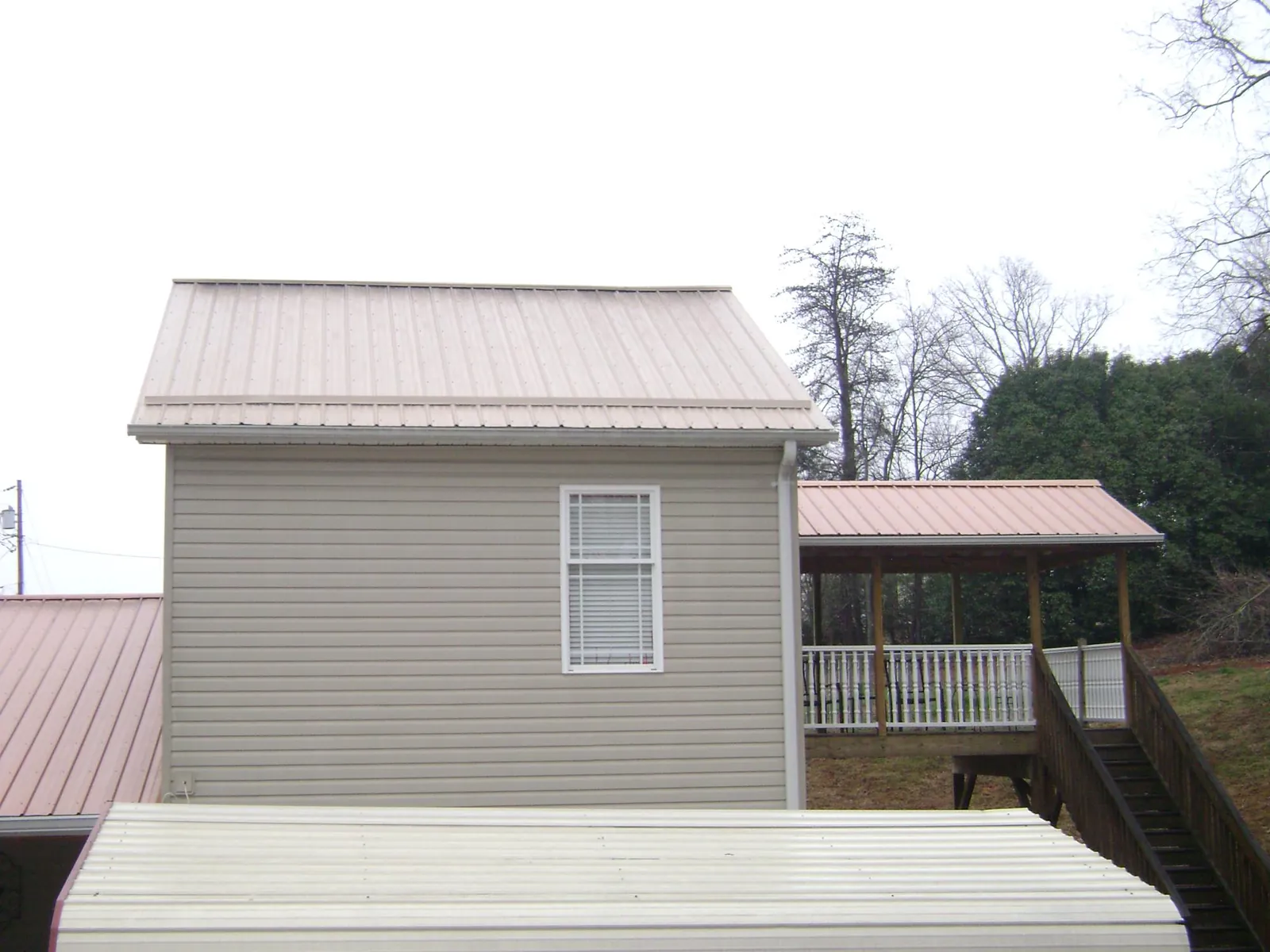 Tan metal roofs on a two story addition and attached porch, from a Roof Replacement job in Hillburn