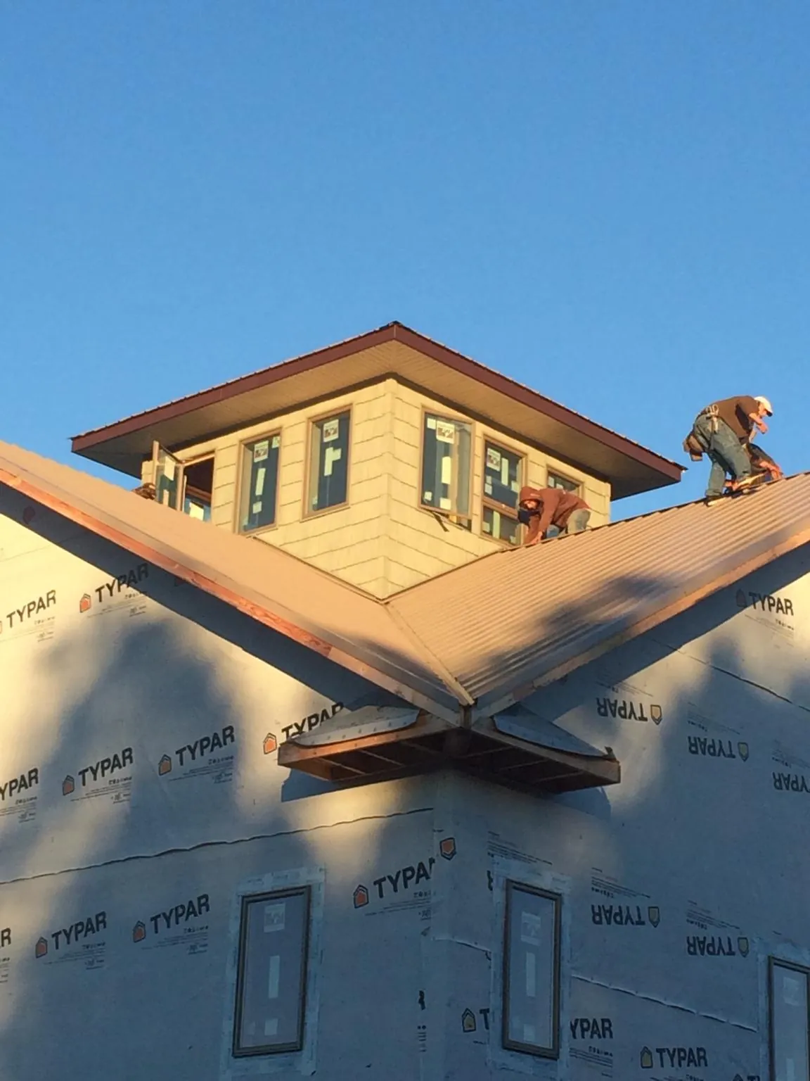 Roofers working around a rooftop cupola on a new metal roof at sunset — Roof Waterproofing in Hillburn by Roofing Brothers